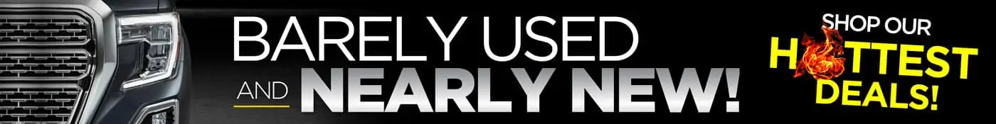 Advertisement for car deals featuring the text Barely Used and Nearly New with Shop Our Hottest Deals and a flaming graphic on a black background. A part of a vehicles front grille is visible on the left side.