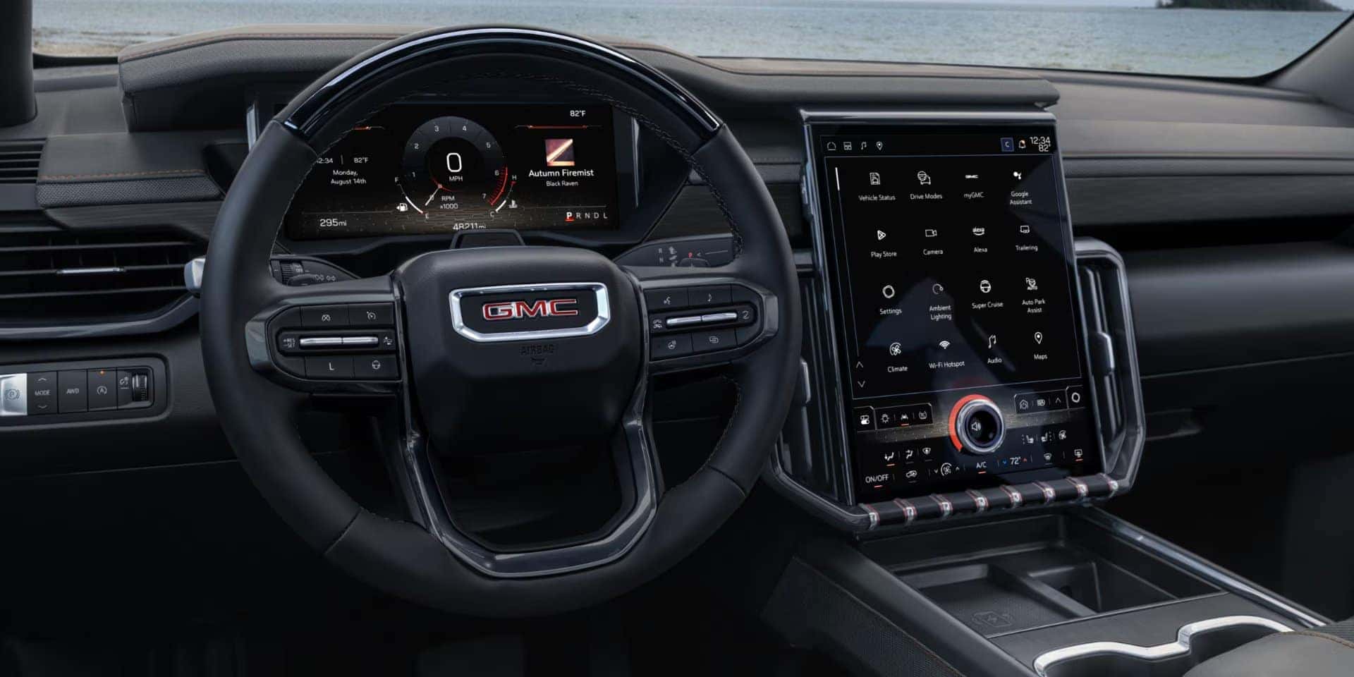 Interior of a modern GMC vehicle featuring a sleek black steering wheel with the GMC logo, a digital dashboard displaying vehicle metrics, and a large touchscreen infotainment system with various app icons and controls. A scenic view is visible outside.