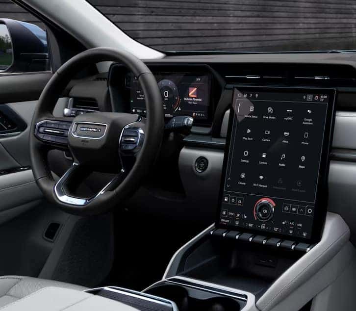 Interior of a modern vehicle featuring a sleek dashboard with a wide touchscreen display. The steering wheel has multiple controls, and the infotainment screen shows various icons and options. The design is minimalistic and high-tech.