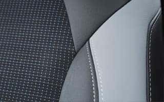 Close-up of a car seat showing a combination of dark gray fabric with small white dots and light gray leather with visible stitching. The design creates a modern and sleek appearance.