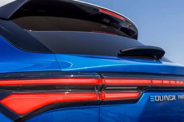 Close-up of the rear of a blue SUV, showcasing sleek red taillights and the word Equinox on the side. The vehicle features a modern and aerodynamic design under a clear blue sky.