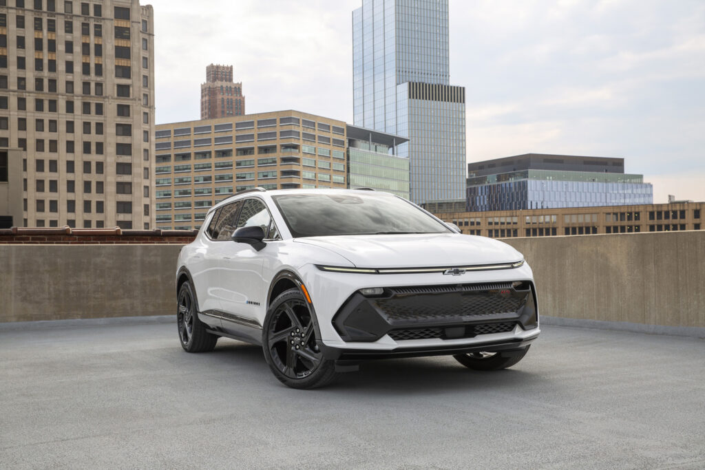 A sleek white SUV parked on a rooftop with city skyscrapers in the background.