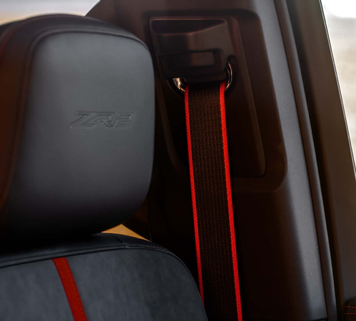 Close-up of a car seat with black and red seatbelt, embossed "ZR2" on headrest.