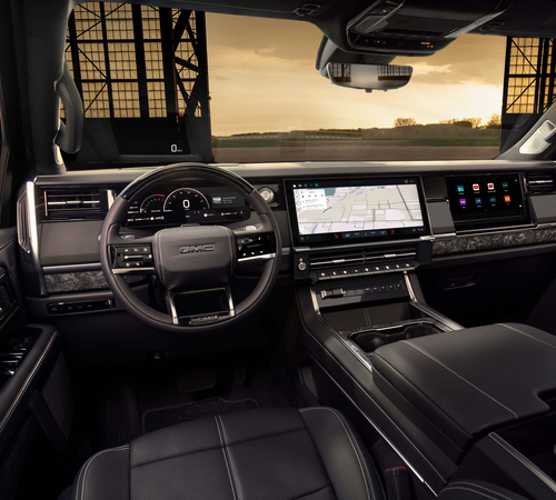 Luxury car interior showcasing a modern dashboard with digital displays and scenic sunset view.