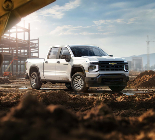 White pickup truck at a construction site with scaffolding and machinery in the background.