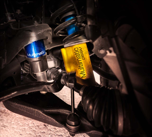 Close-up of a car suspension system featuring Multimatic DSSV dampers with a blue and yellow casing.