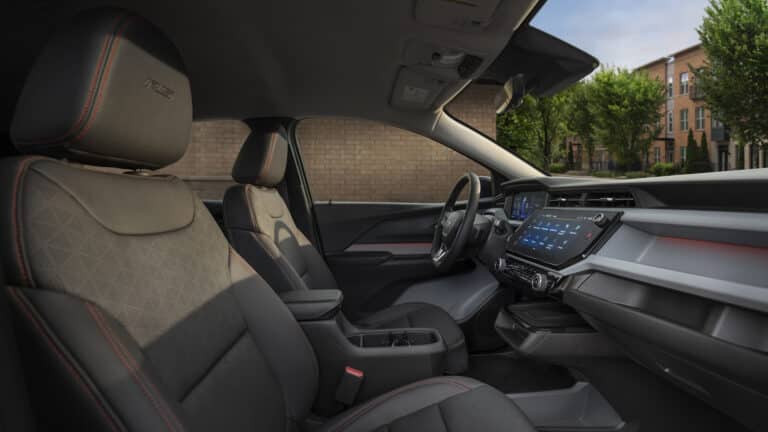 Modern car interior with touchscreen display, leather seats, and red stitching accents.