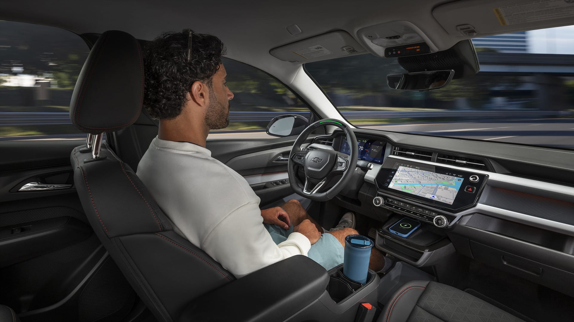 Man sitting in a self-driving Chevrolet car, displaying an advanced dashboard and navigation.